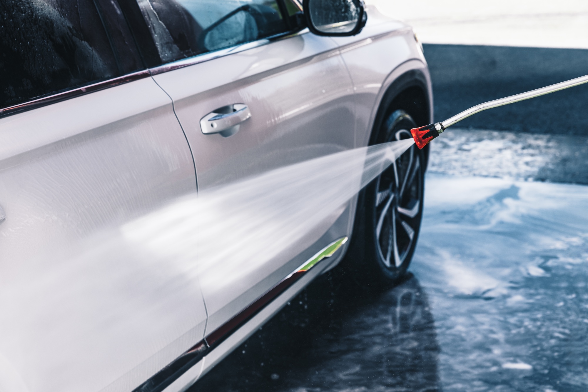 The car is washed at a car wash with a high pressure washer. High-pressure car wash